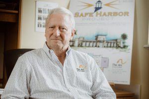 neal benson sits in front of a rendering of the arc of the st johns safe harbor project